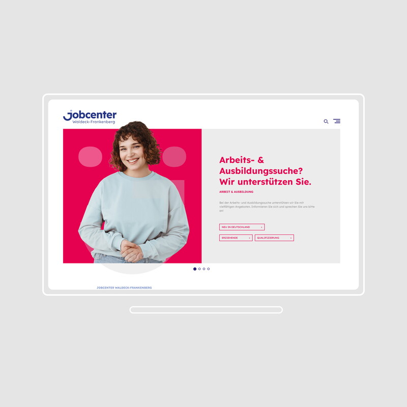 Eine grafische Ansicht der Website vom Jobcenter in Form eines Computers, wo eine Frau lächelnd vor einem pinkem Hintergrund steht