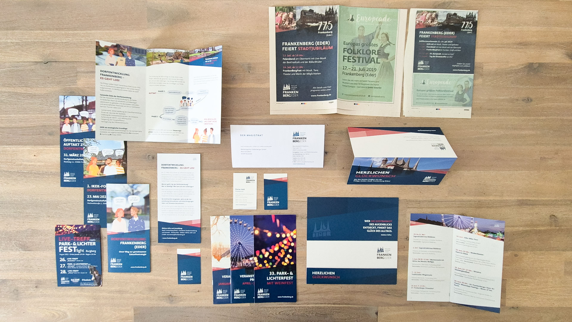 Verschiedene Broschüren und Flyer der Stadt Frankenberg liegen verteilt auf einem Holztisch
